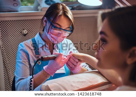 Nail treatment process at manicure studio. Customer is reciving good service from expirienced master.