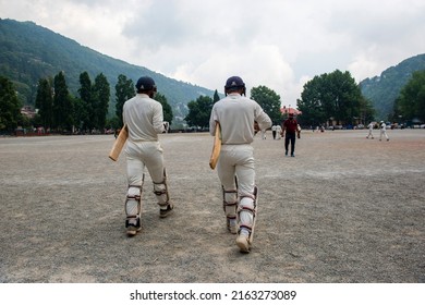 Nainital, Uttarakhand, India-May 6 2022: Cricket batsman, shot from behind heading out to bat in local field in Nainital public ground, Batsman heads out onto the field to face up 
