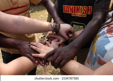 Nairobi, Kenya - January 19, 2015: Black African Men And White Caucasian People Twisted Their Arms And Hold Each Other In A Symbol Of Friendship And Protest Against Racism.