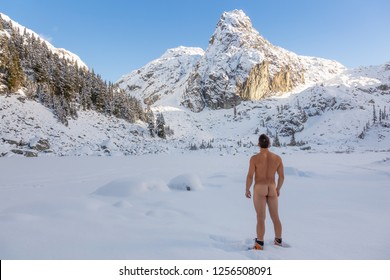 Naked Adventurous Man enjoying the beautiful Canadian winter landscape during a bright sunny day. Taken in Watersprite Lake, near Squamish, North of Vancouver, BC, Canada.