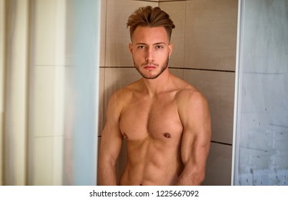 Naked Athletic Young Man Taking Shower in the Bathroom to Refresh While Leaning Against Glass Door, Covering Groin with Hand, Looking at Camera
