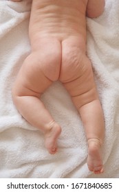 Naked Baby Butt And Legs On White Bed. Dry And Healthy Body And Skin,