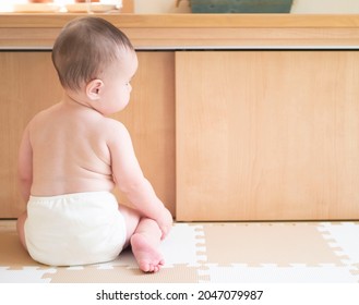 Naked baby in cloth diaper tries to stand 