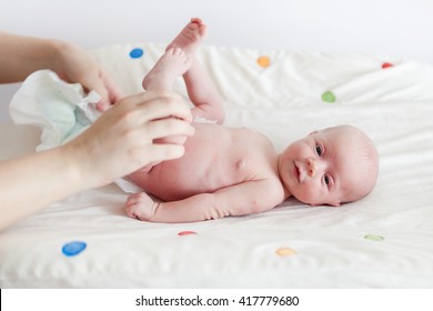 Naked baby girl on changing table getting diaper changed.