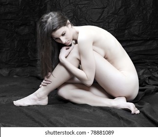 Naked beautiful woman posing on black background.