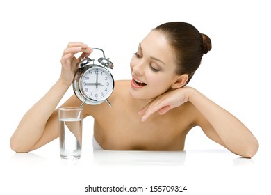 Naked Girl With Glass Of Water Hands Alarm Clock And Looks At It, Isolated On White