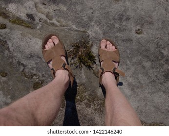 Naked Hairy Male Legs With Leather Sandals Rest While Trail. Person Enjoy Fantastic View Into Wild Landscape And Gains Again Power.