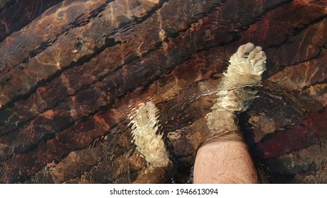 Naked hairy male legs walk on pier. The legs of a man swim. First person of view. Men rest on a flood wood underwater pier.