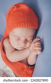 A Naked Newborn Baby Sleeps In A Christmas Hat.