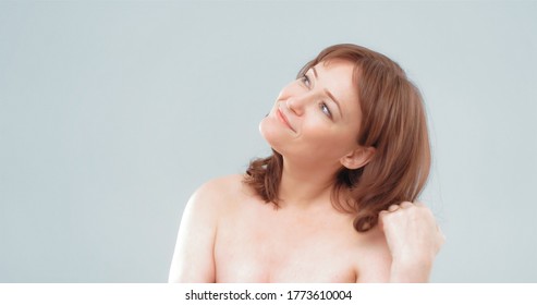 Naked woman smiles looking aside. Pretty mature female touching her long hair with hand, cut out on light gray background. Spa and wellness concept. - Shutterstock ID 1773610004