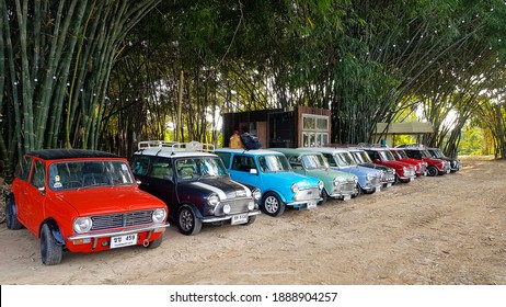 Nakhon Nayok, Thailand -December 5, 2020: Many Austin Mini Cooper Or Classic Car Parked On Street With Bamboo Forest And House Or Home Background With Copy Space. Group Of Vintage Or Retro Vehicle. 