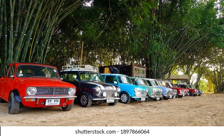 Nakhon Nayok, Thailand -December 5, 2020: Many Austin Mini Cooper Or Classic Car Parked On Street With Bamboo Forest And House Or Home Background With Copy Space. Group Of Vintage Or Retro Vehicle. 