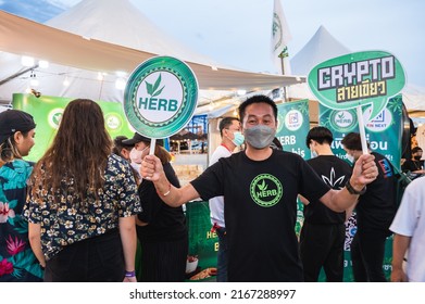 Nakhon Pathom, Thailand. June 11, 2022. Outdoor Cannabis Event In Nakhon Pathom After The Thai Government Legalization. A Person Holding Signage Of HERB Crypto, A Crypto Project Related To Cannabis.