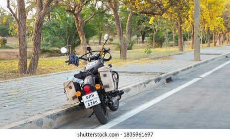 Nakhon Pathom, Thailand - September 24, 2020 : Photo of Motorbike Royal Enfield of travelers taking a break on along the  main road with beautiful blooming yellow flowers at Nakhon Pathom Province.