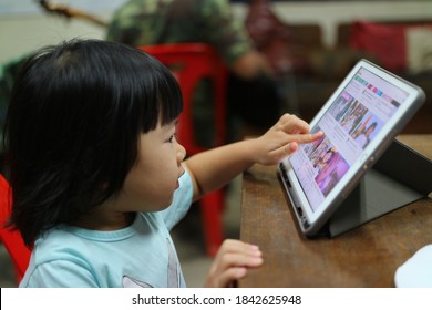 Nakhon Sawan, Thailand, 27 October 2020, 3 Year Old Cute Asian Girl Is Enjoying Watching Movies, Cartoons, Learning, Online Education From IPad.