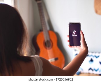 Nakhonratchasima, Thailand, May 6, 2020 : Young Asian Woman Using TikTok Application On IPhone At Home