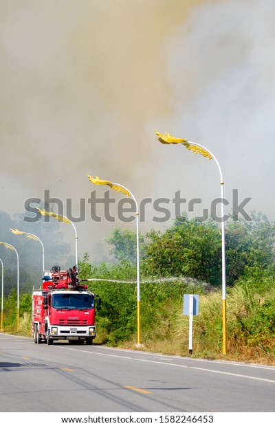 Nam Rin Road, Ban Chang, Rayong, Thailand,\
Sunday, December 8, 2019, Fire Fighter on the red fire truck try to\
control and stop the\
wildfire.