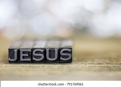 The name JESUS concept written in vintage retro metal letterpress type on a wooden background.
