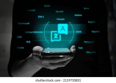 The Name Of The Language With Translation To The Original. The Person Is Holding A Smartphone With A Hologram.