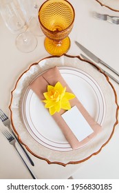 Name Plate Mockup With Empty Card Laying On The Table Decorated For Wedding Banquet. Invitation Template For The Inscription Of The Guest On A White Plate With Napkin And Narcissus Flower