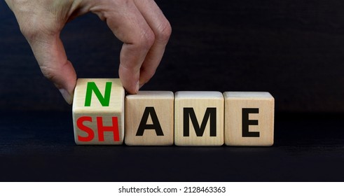 Name or shame symbol. Businessman turns the wooden cube and changes the concept word Shame to Name. Beautiful grey table grey background, copy space. Business, name or shame concept.