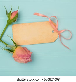 Name tag with Peachy Pink Rose Bud and Bow on Shabby Chic, Distressed Teal Wood Board Background. The card is blank for your words, text, or copy. A photo taken from up above for flat lay design Foto Stock