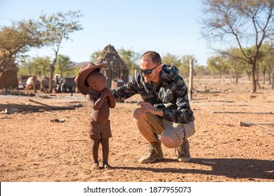 Namibia, Africa, July 18, 2019. European man, tourist plays with a boy from the Himba tribe. Namibia