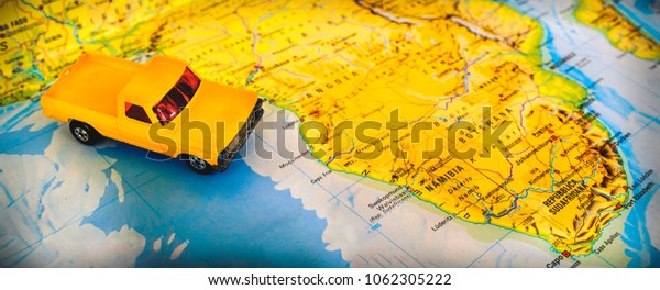 Namibia, South Africa, 04 April 2018 - Geographic\
paper map Safari road trip in south africa desert with orange\
pickup car truck toy