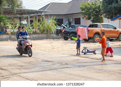 Nan, Thailand, Apr 13, 2019 - Group of kids splashing water to girls driving motorbike on Songkran festival day 