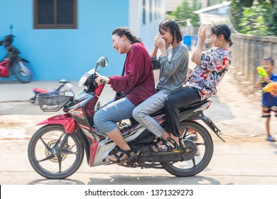Nan, Thailand, Apr 13, 2019 - Group of kids splashing water to girls driving motorbike on Songkran festival day 