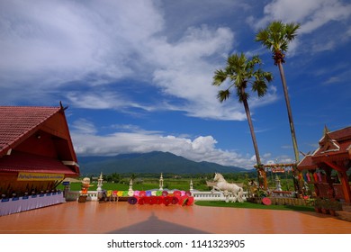 Nan, Thailand - July 23, 2018 : Inside Wat Si Mongkol There are beautiful Viewpoint, Includes Doi Phu Kha mountains in the background, many colorful umbrella, house statue, two tall trees.