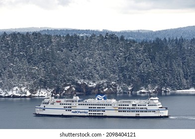 Nanaimo, Canada - December 28, 2021: A BC Ferries car and passenger ship leaves the terminal in Nanaimo on its way to Vancouver, passing a snow covered Newcastle Island on the way.