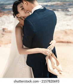 Đa Nang City, Vietnam - August 2021: Bride And Groom Kiss Romantically On The Beach