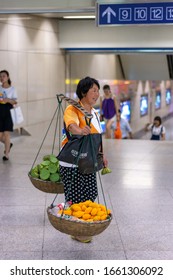 Nanjing / China - July 30, 2015: Woman With A Wooden Carrying Pole Selling Fruits And Water In Nanjing Subway