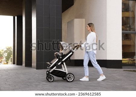 Nanny with cute little boy in stroller walking outdoors