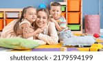 Nanny and cute little children in playroom
