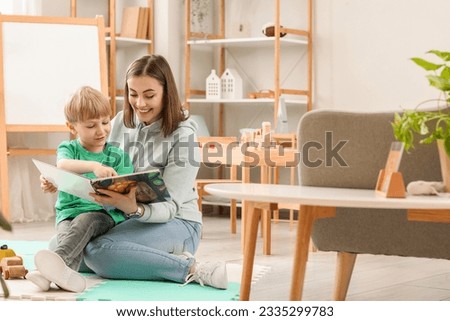 Nanny with little boy reading story at home