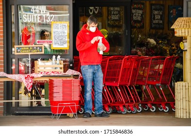 Naperville, IL - 4/16/20: Trader Joes Grocery Store Worker Wearing N95 Respirator Mask And Gloves While Using Disinfectant Spray To Protect Shoppers From Contracting Covid19 During The Global Pandemic