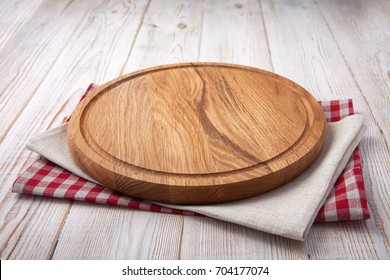 Napkin and board for pizza on wooden desk. Stack of colorful dish towels on white wooden table background top view mock up. Selective focus. - Shutterstock ID 704177074