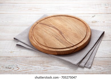 Napkin and board for pizza on wooden desk. Stack of colorful dish towels on white wooden table background top view mock up. Selective focus. - Shutterstock ID 705275047
