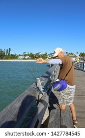 Naples, FL/USA: Feb 28, 2019 - Fisherman On Naples Pier In Florida Catches Catfish, Scientific Name Siluriformes. Beach And High End Housing In Background. 