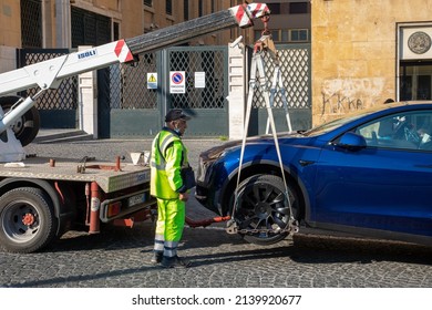 Naples, Italy - March 25, 2022: Removal with the tow truck of a parked car in no parking. Fine and removal of a Tesla brand electric car.