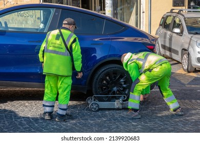 Naples, Italy - March 25, 2022: Removal with the tow truck of a parked car in no parking. Fine and removal of a Tesla brand electric car.