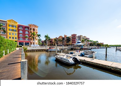 Naples, USA - April 30, 2018: Bayfront residential community center with water harbor marina dock boardwalk and boats palm trees sun flare