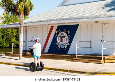 Naples, USA - April 30, 2018: Florida Gulf Of Mexico City With Woman Riding Segway By US Coast Guard Auxiliary Building Sign For Coastal Guard Patrol In Summer