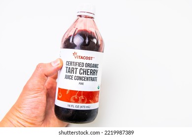 Naples, USA - October 21, 2021: Hand Holding Closeup Of Glass Drink Bottle Of Tart Organic Cherry Juice Concentrate By Kroger Vitacost Brand