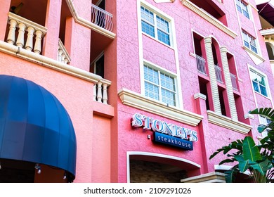 Naples, USA - September 13, 2021: Naples, Florida Bayfront Condo Colorful Pink Coral Spanish Architecture Building With Sign For Stoney's Restaurant Steakhouse Fine Dining