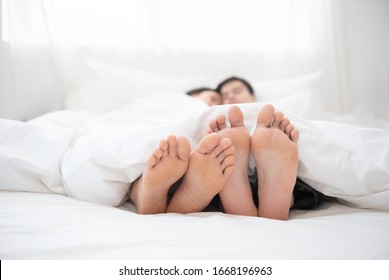 Napping Man Woman Barefoot Lying Under Covers Bed Hotel Room, Closer Up On Couple Feet.