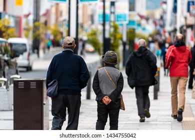 Nara, Japan - April 14, 2019: Back Of People Tourists Senior Couple Walking On Sidewalk Street Road In Downtown City Towards Park