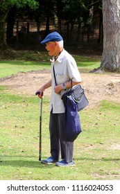 NARA, JAPAN - May 29, 2018. Elderly Japanese Man With Cap And Walking Stick Enjoys Nature In Outdoor Park. Aging Population.